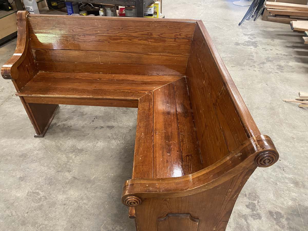 One of the original carved scroll ends, with the seat and back running toward the mitered corner