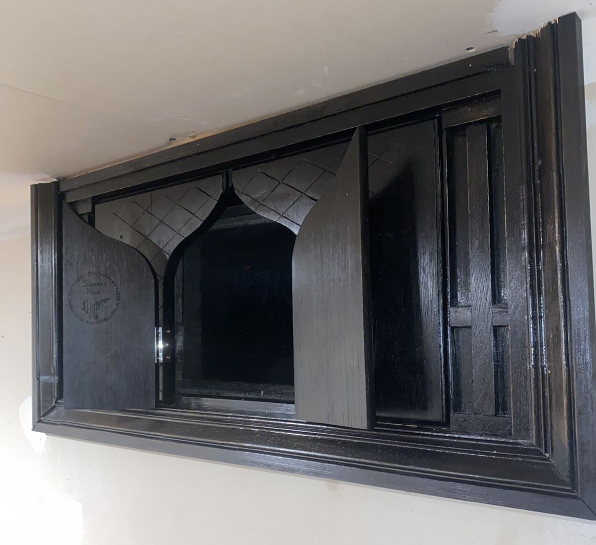 The same shutters with the doors swung open, showing the ogee arch cut into their inner edges